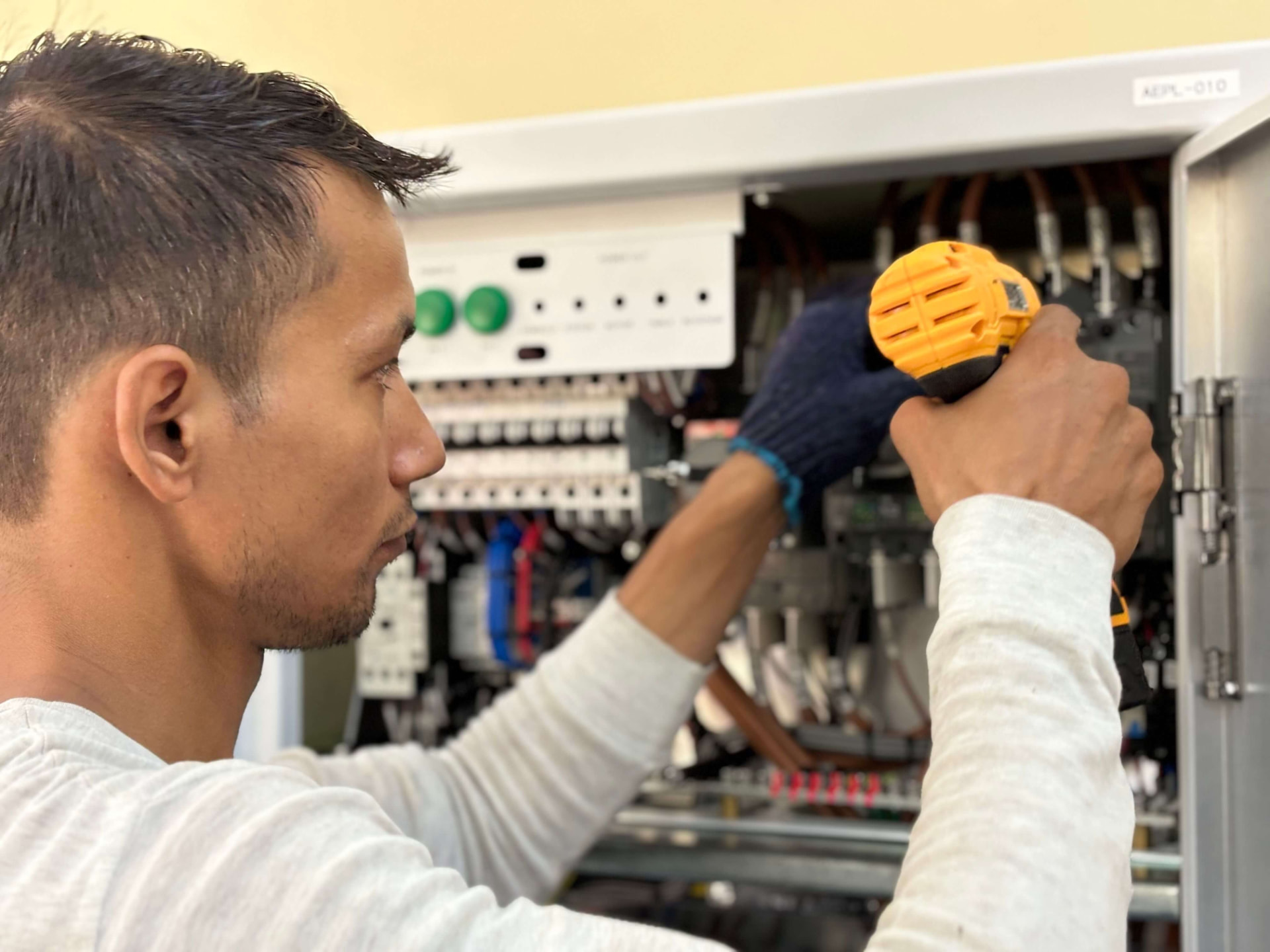 Elektricien werkt met een accuschroevendraaier aan een elektrische verdeelkast